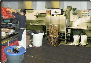 Youth working in restaurant washing and stacking dishes