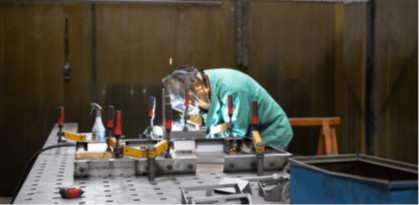 Grenzebach employee welding parts in appropriate personal protective equipment (PPE).