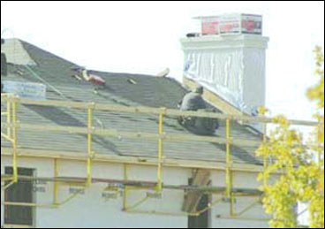 Figure 10 - An exterior bracket scaffold with guardrails being used to protect workers while weatherproofing. For problems with accessibility in using figures and illustrations, please contact the DOC at 202-693-2020.