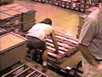 Worker bending to lift pallets from floor