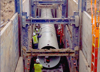 Workers building underground pipeline in trench